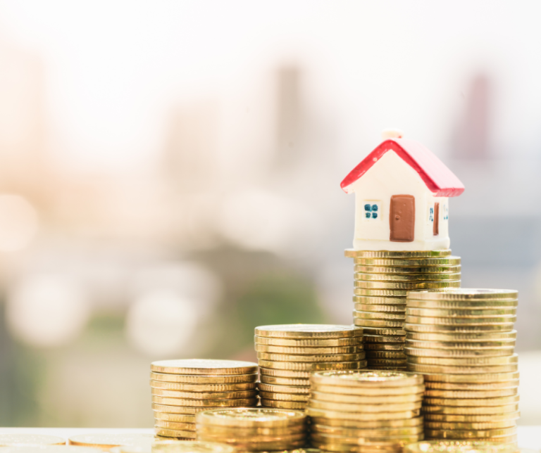 דגם בית קטן מונח על ערימת מטבעות זהב – המחשה של תמחור נכס נדל"ן