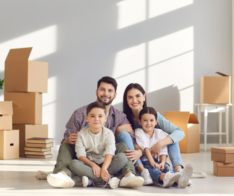 משפחה צעירה יושבת בסלון בין קרטוני אריזה ומתכוננת לבדיקות לפני קניית דירה חדשה